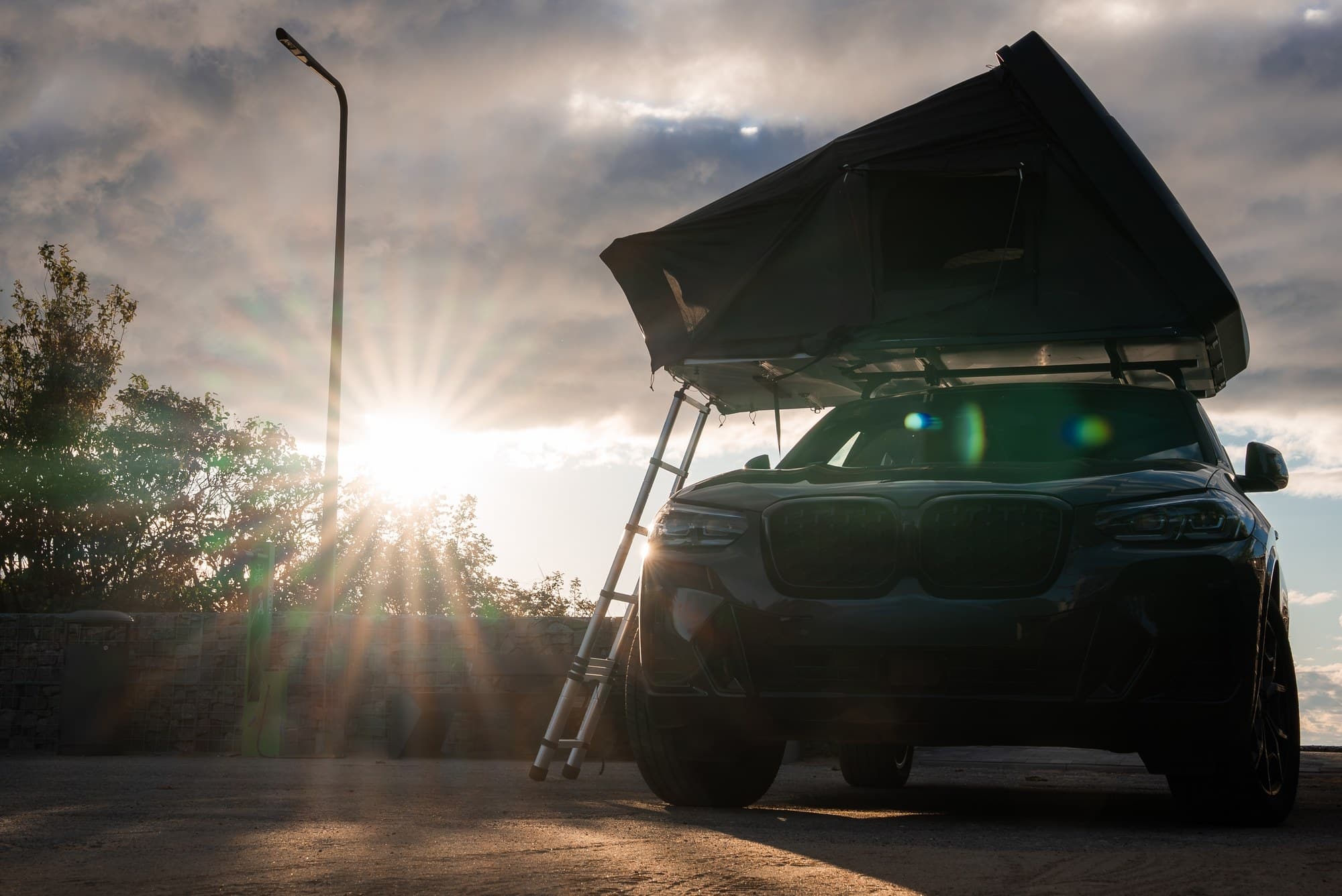 Rooftop tent on an SUV SUV with an open rooftop tent parked at sunset
