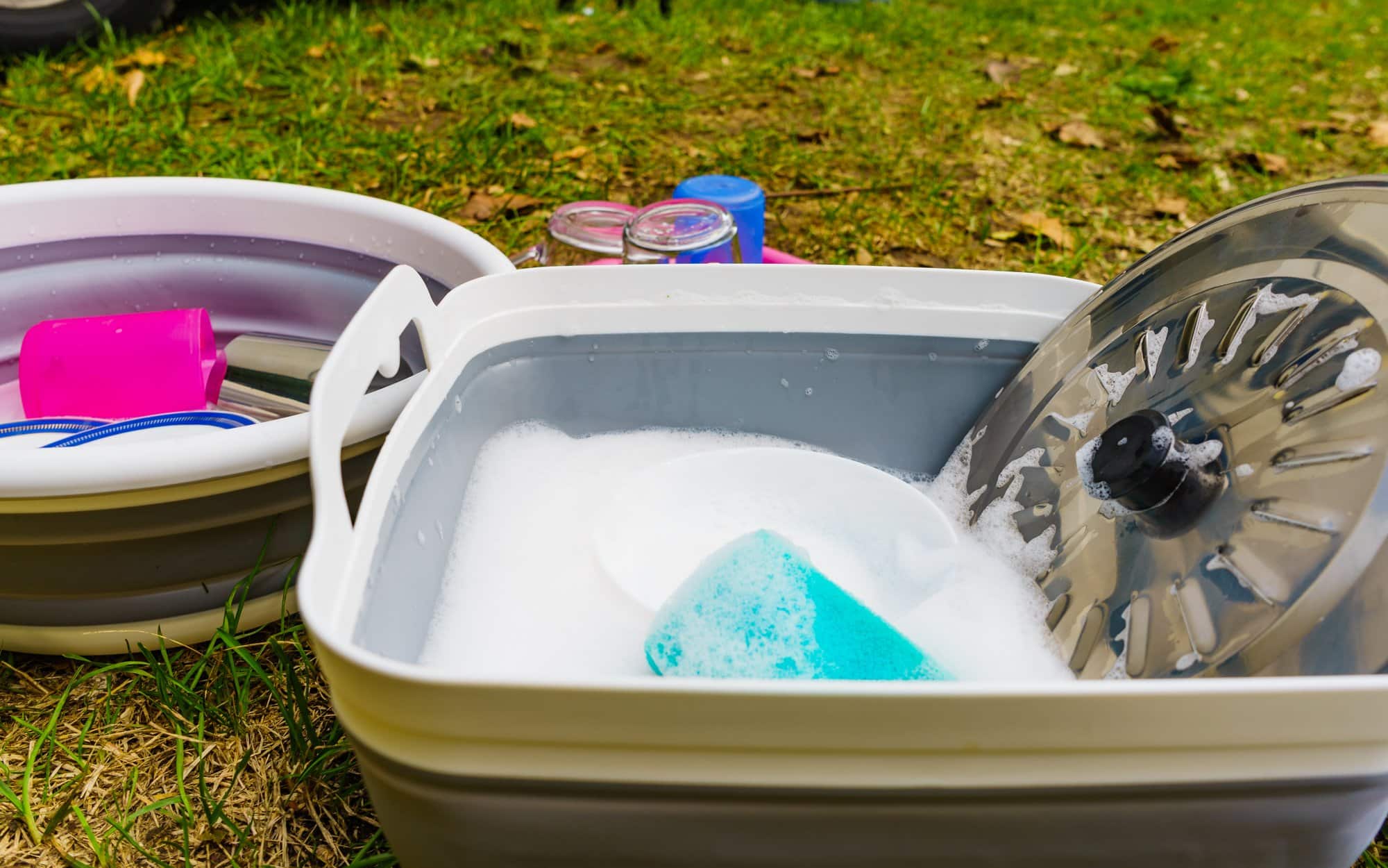 Washing camp cookware at camp Collapsible wash basin with soapy water and a camp plate at a campsite