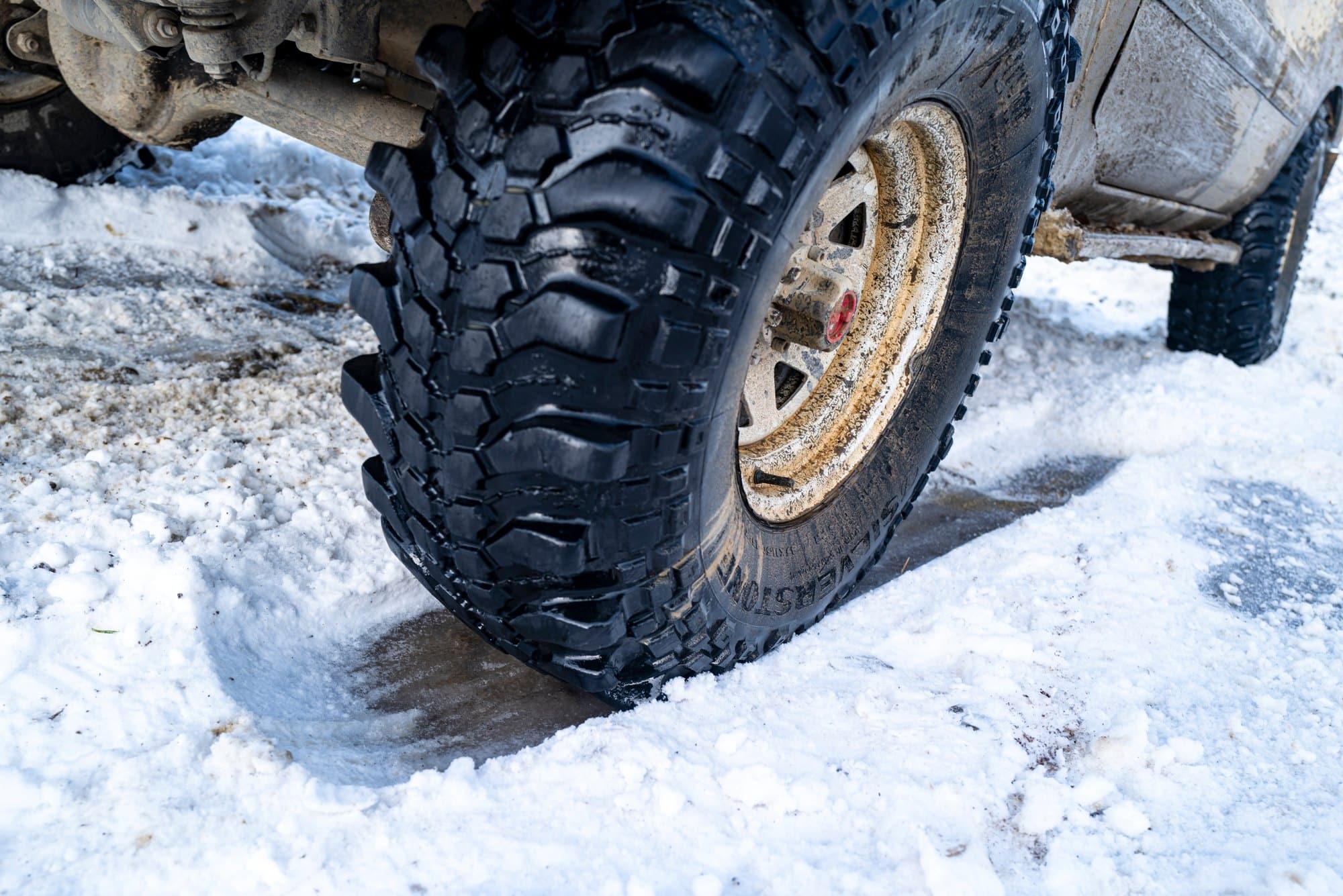 Off-road tire on a snowy road Close-up of an aggressive off-road tire on a snow-covered road