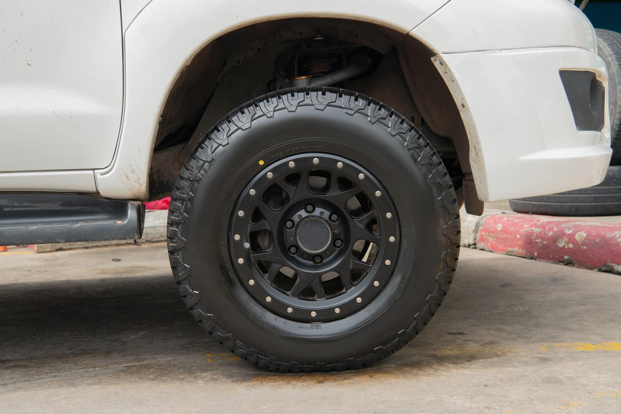 All-terrain tire on a white pickup truck All-terrain tire with a deep tread pattern on a white pickup truck