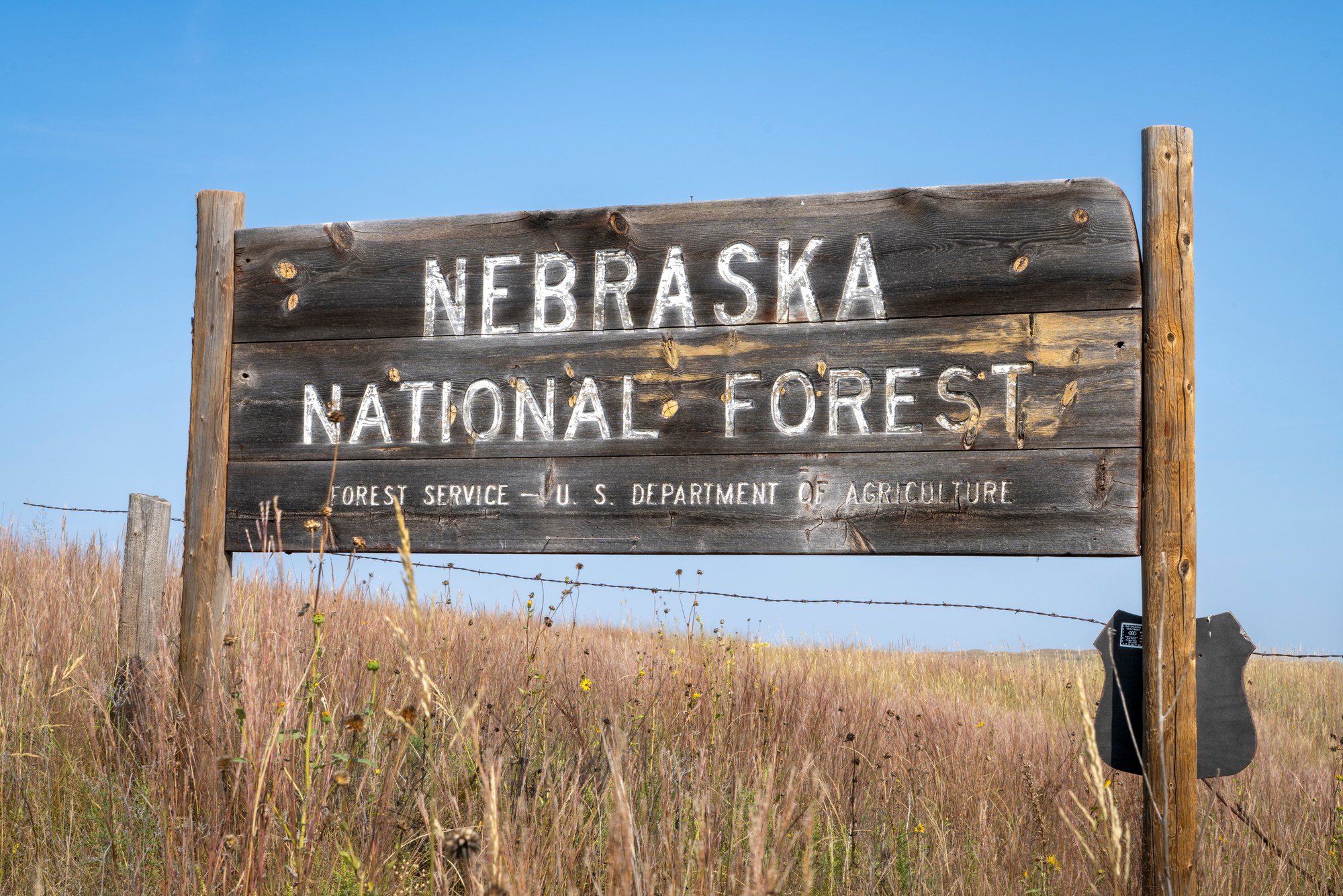 National forest entrance sign Weathered Nebraska National Forest sign beside a prairie fence line