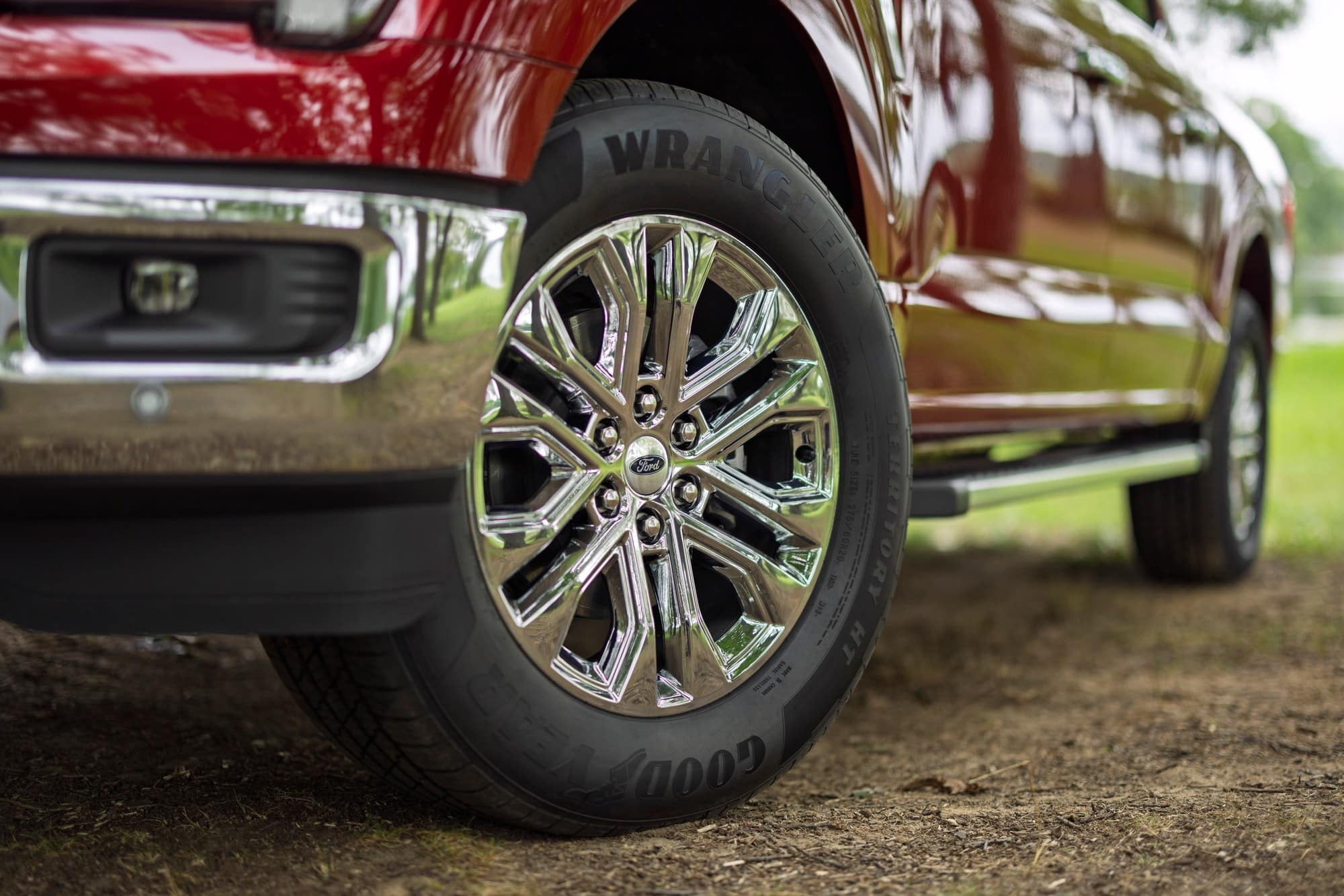 Chrome wheel and front bumper of a red 2027 Ford F-150 Lariat