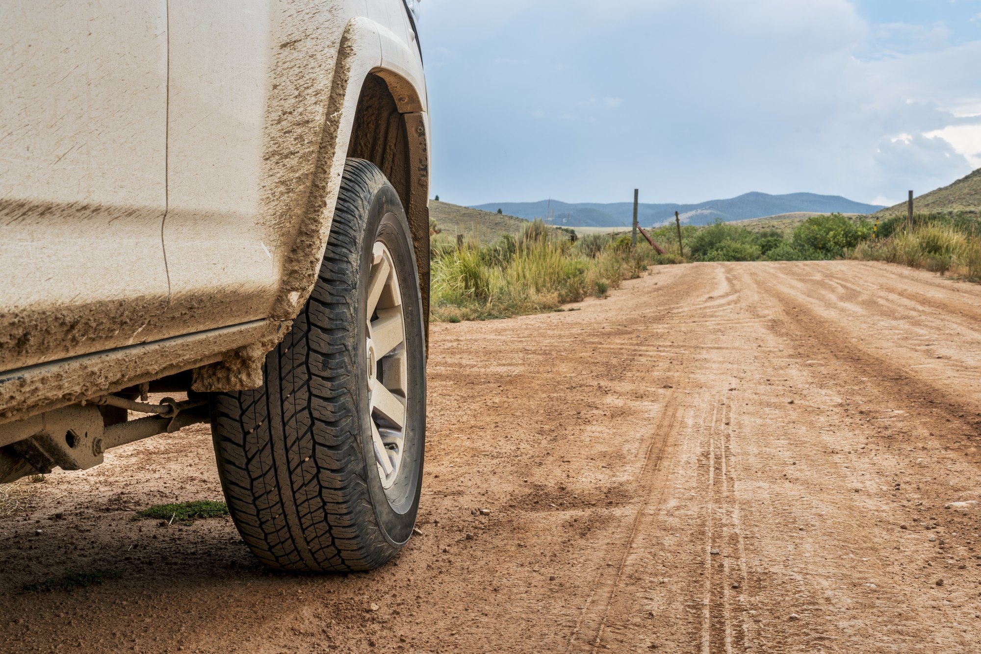 4x4 SUV on a dirt road Muddy 4x4 SUV tire on a dusty dirt road through open country