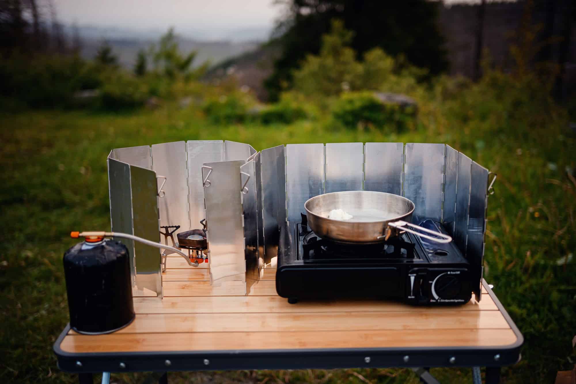 Folding wind screen at a campsite Folding aluminum wind screen around a portable gas stove on a camp table