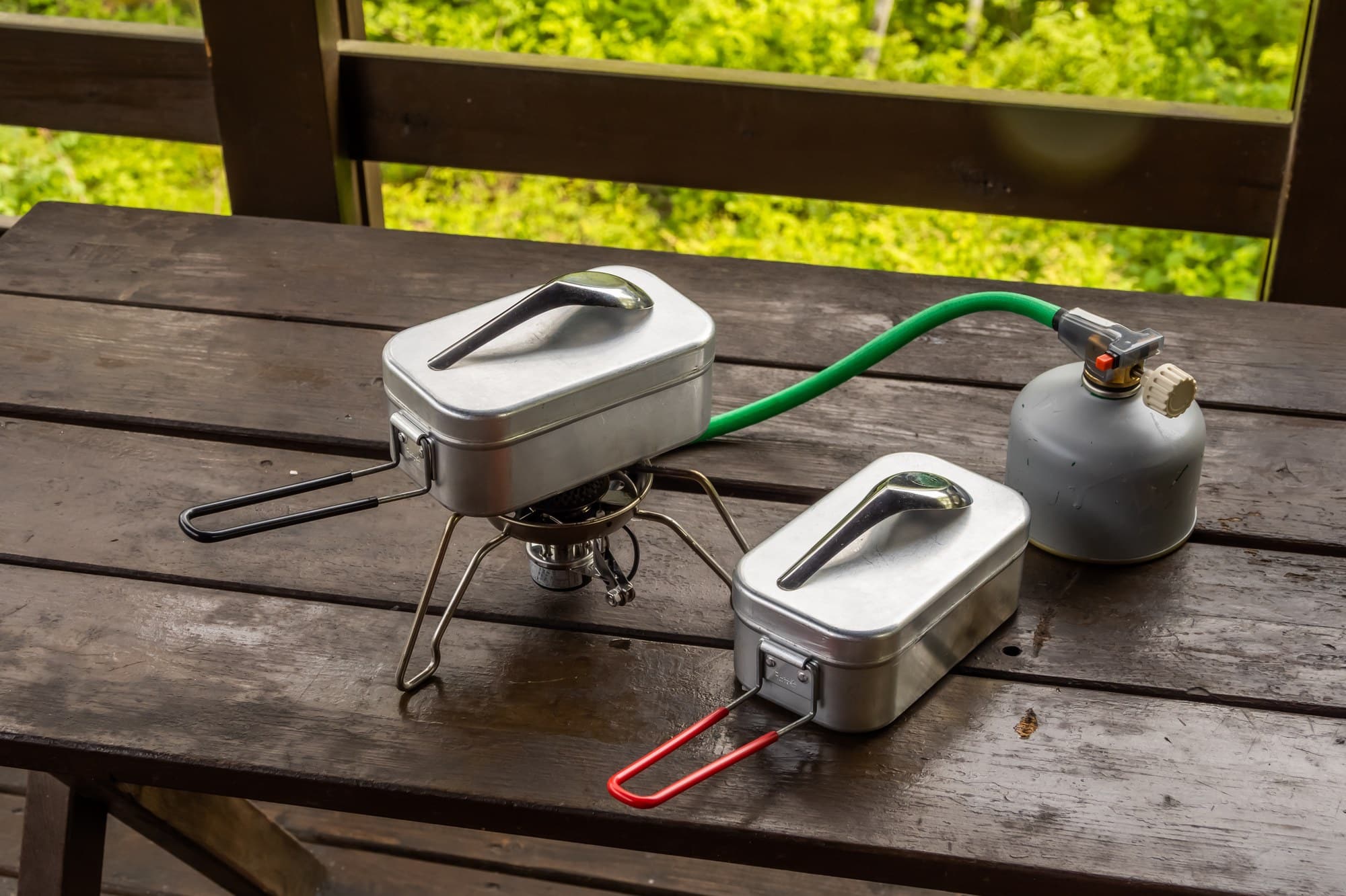 Camp stove fuel hose hookup Portable camp stove connected to a fuel canister with a hose on a wooden table
