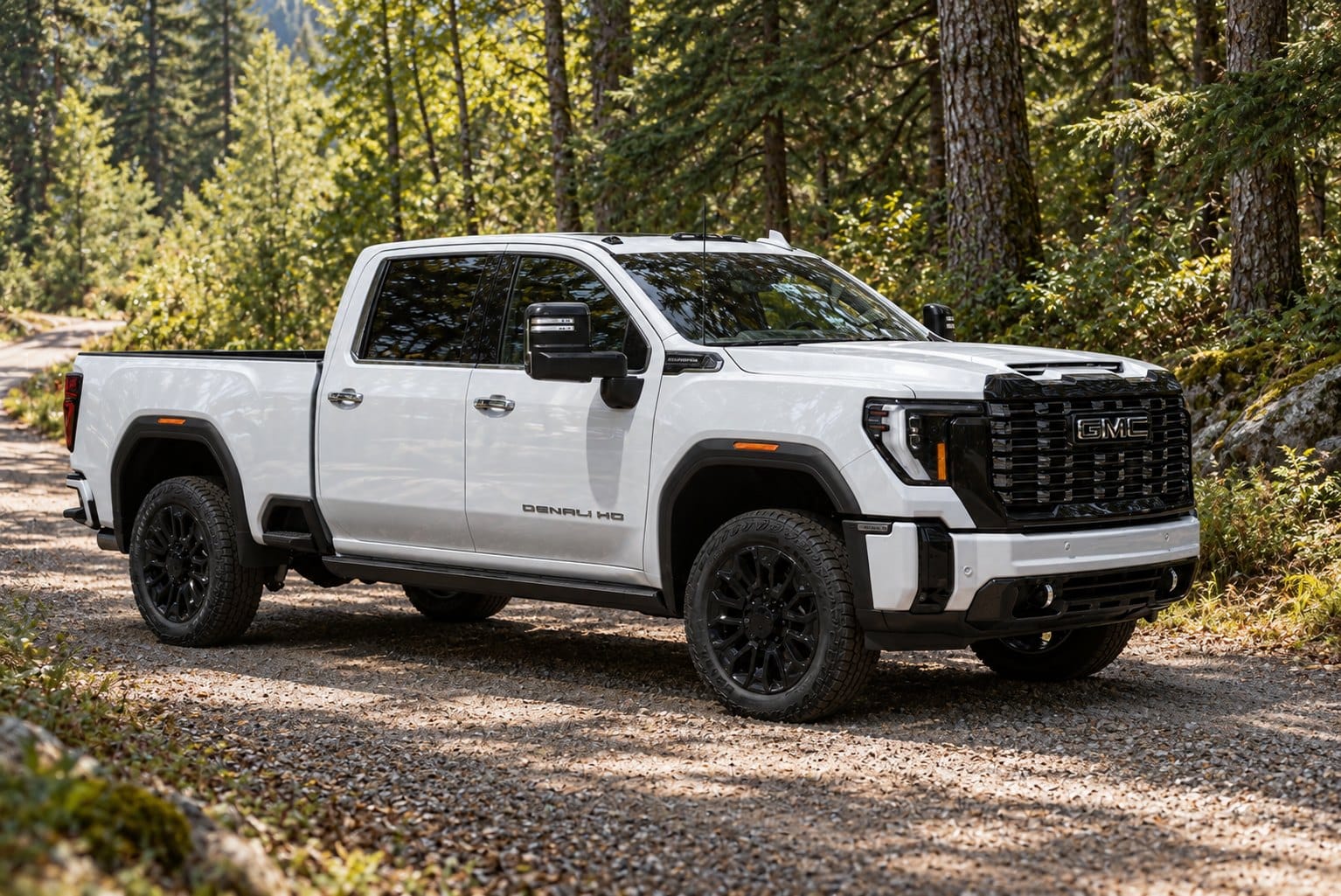 White GMC Sierra Denali HD crew cab on a gravel forest road, a heavy-duty pickup covered by federal rules on diesel tuners