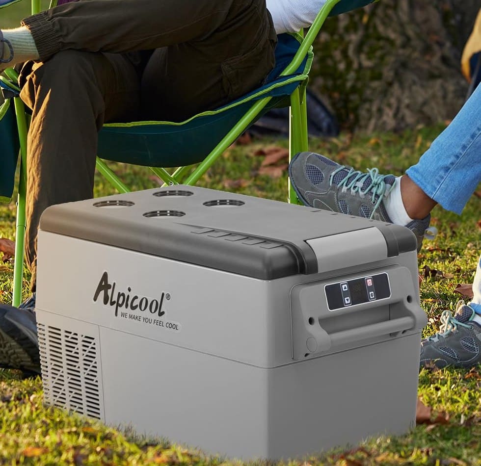 Alpicool CF45 compressor fridge at a campsite Alpicool CF45 compressor fridge on the grass beside camp chairs
