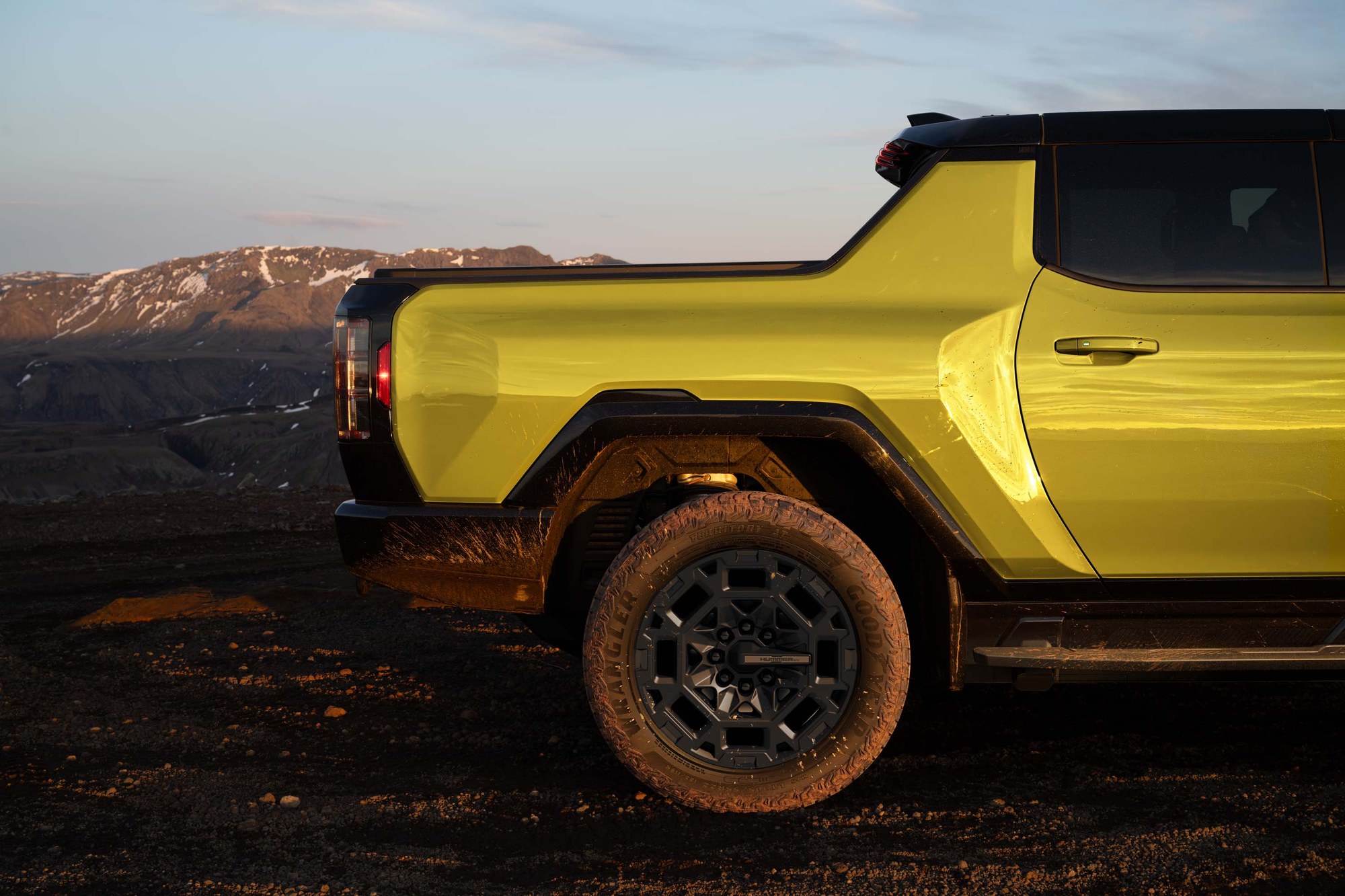 2027 GMC Hummer EV pickup bed and rear tire Bed and muddy rear mud-terrain tire of a yellow 2027 GMC Hummer EV pickup