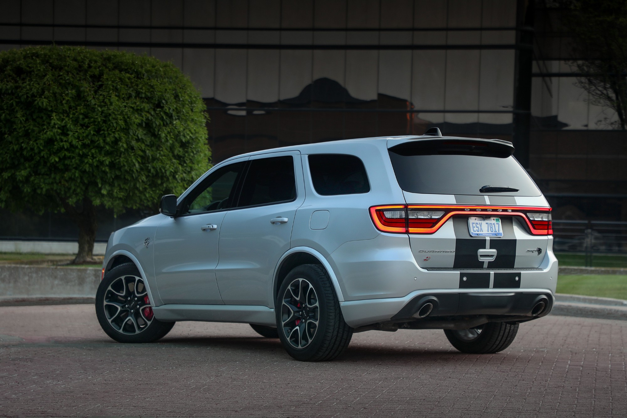 Silver 2024 Dodge Durango SRT with a center stripe, rear three-quarter view with the liftgate racetrack taillamp lit