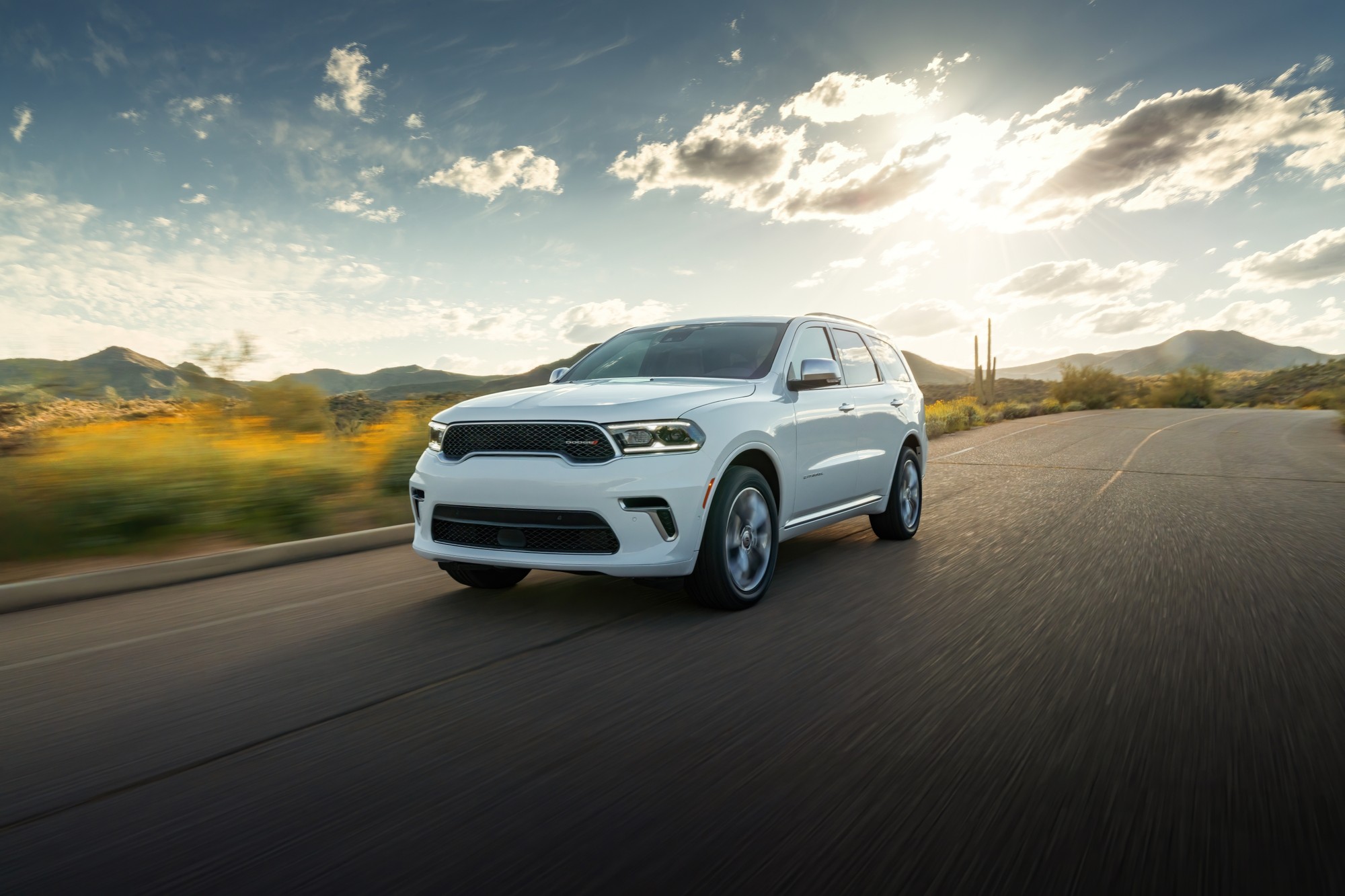 White 2024 Dodge Durango driving on a desert road at sunset