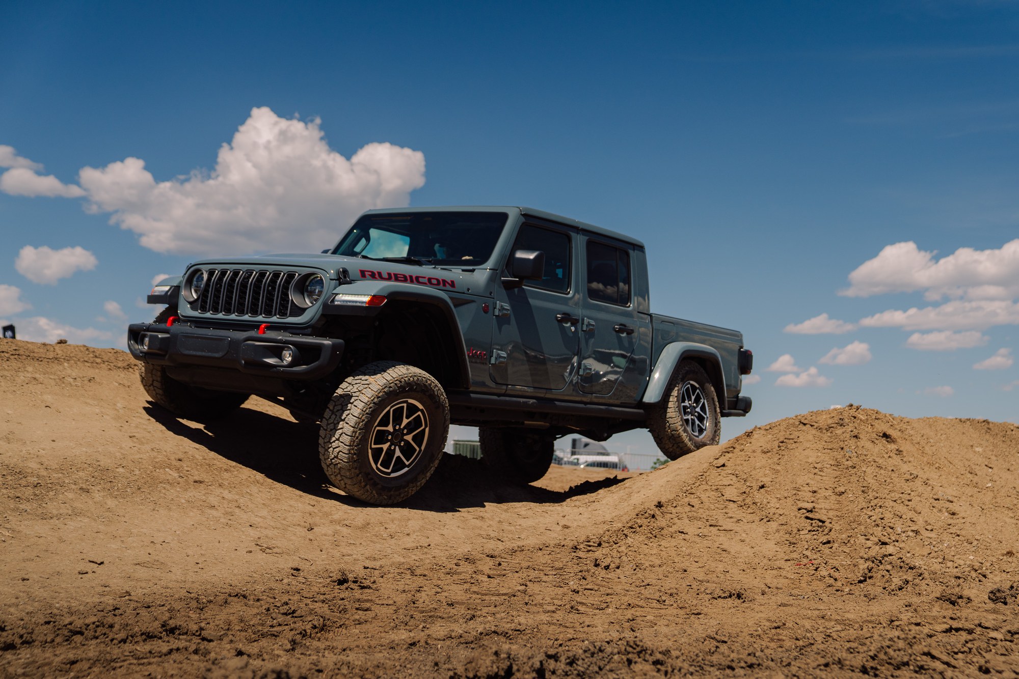 Jeep Gladiator Rubicon on the Ride and Drive course Gray Jeep Gladiator Rubicon climbing a dirt mound on a Jeep Ride and Drive course at Overland Expo