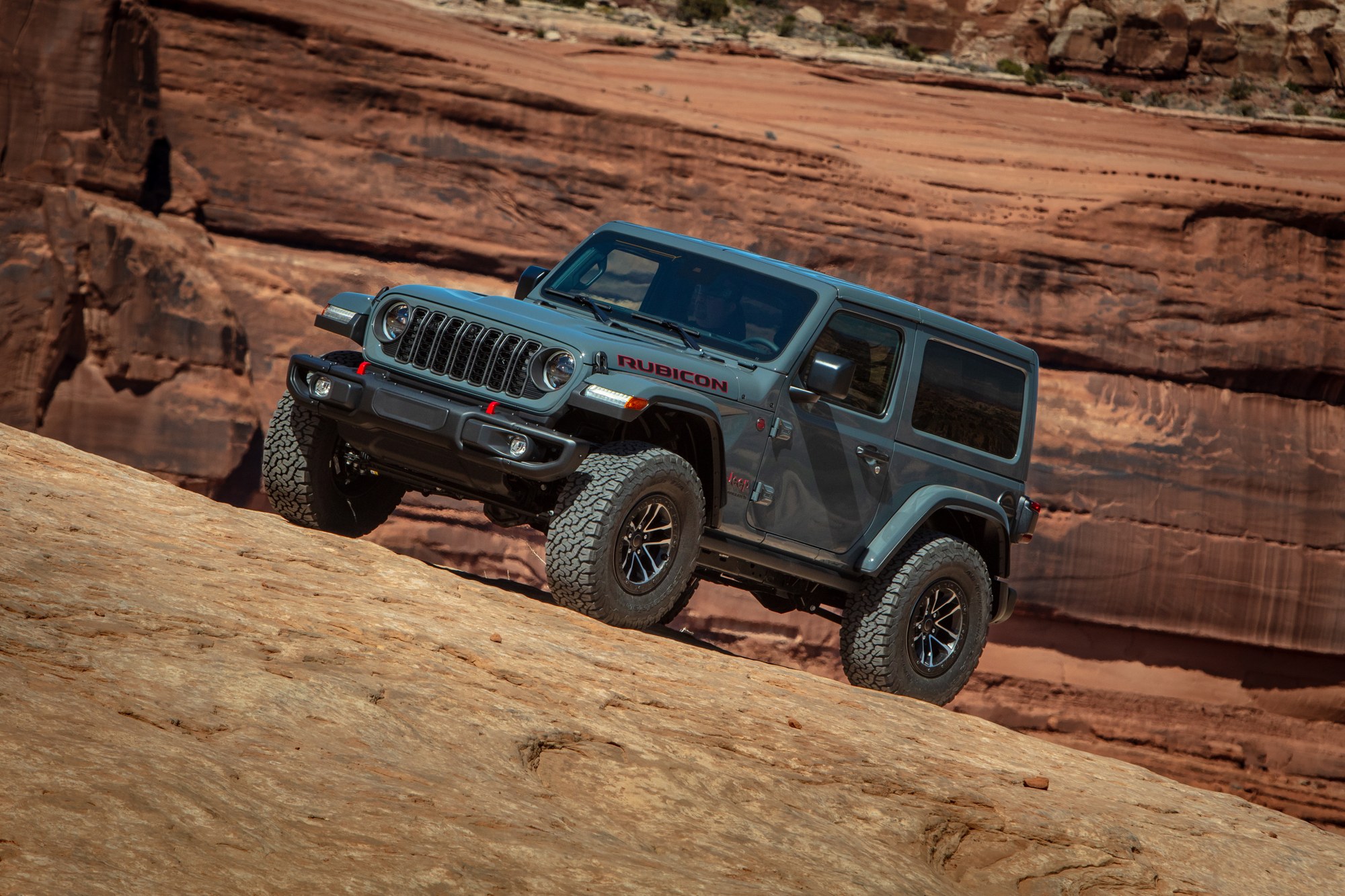 2026 Jeep Wrangler Rubicon two-door with 35-inch tires climbing slickrock