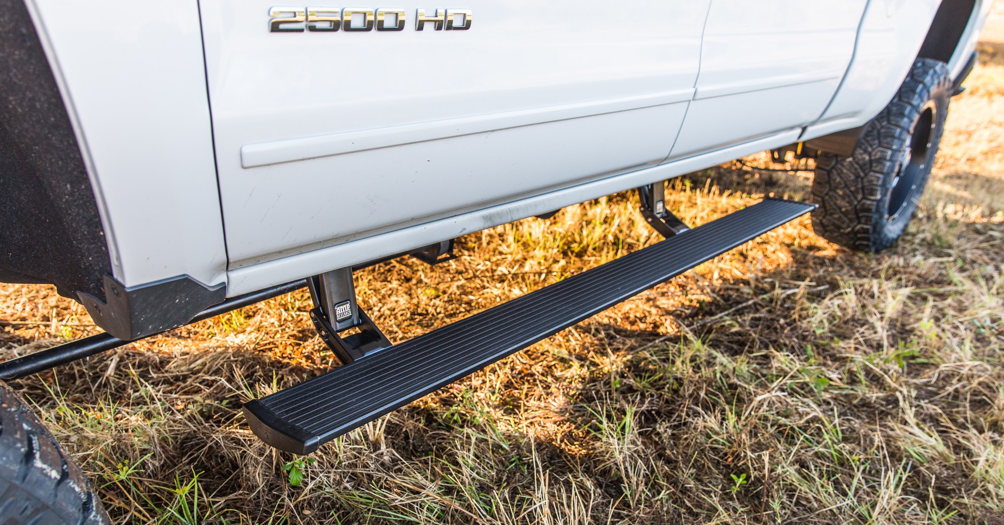 AMP Research PowerStep on a Chevy Silverado AMP Research PowerStep powered running board deployed on a white Chevy Silverado 2500 HD