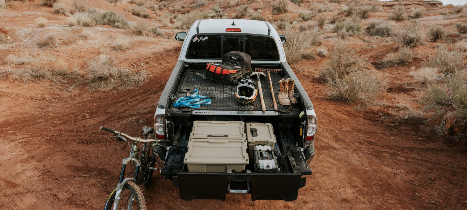 Open DECKED drawer in a fourth gen Toyota Tacoma bed loaded with bike gear in the desert