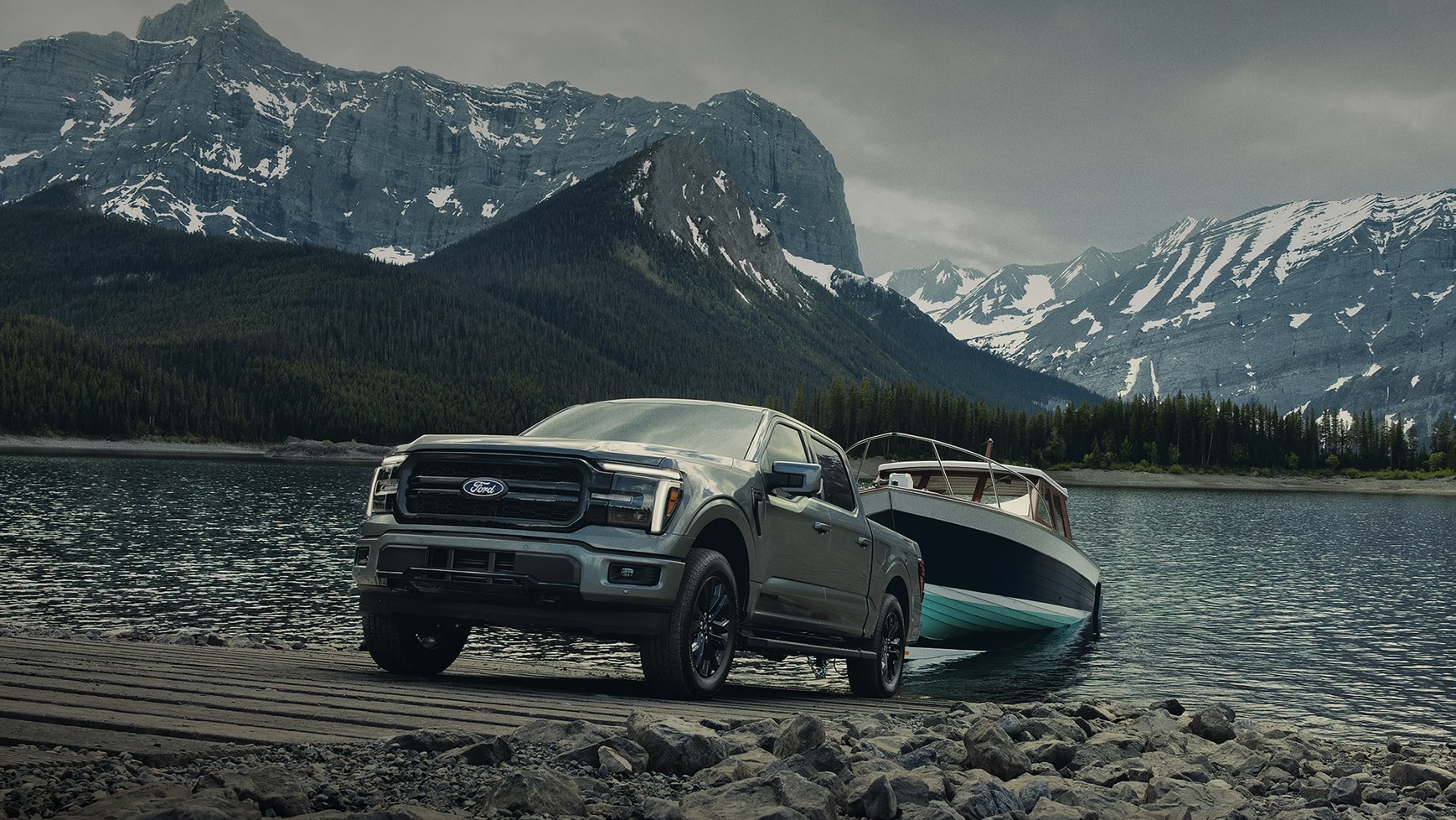 2026 Ford F-150 Lariat backing a boat trailer down a launch ramp at a mountain lake