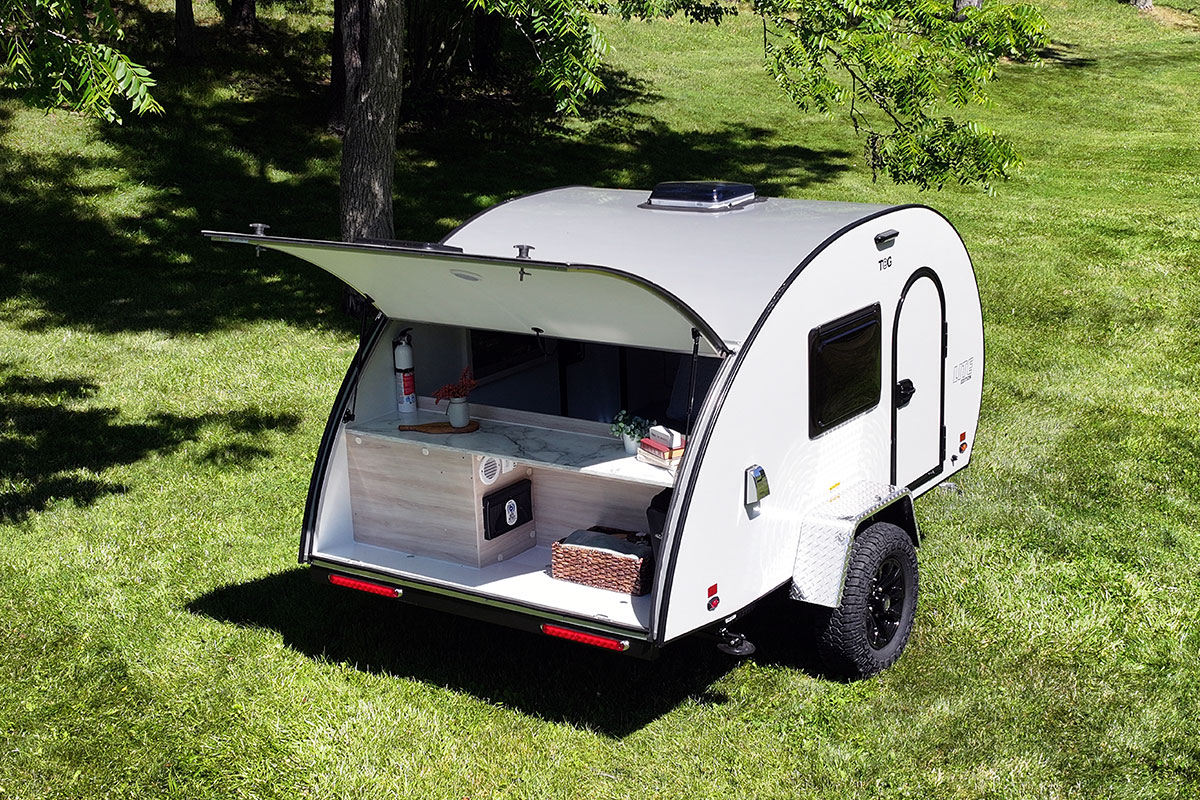 Open rear hatch of the nuCamp TAG XL LITE trailer on a grassy field